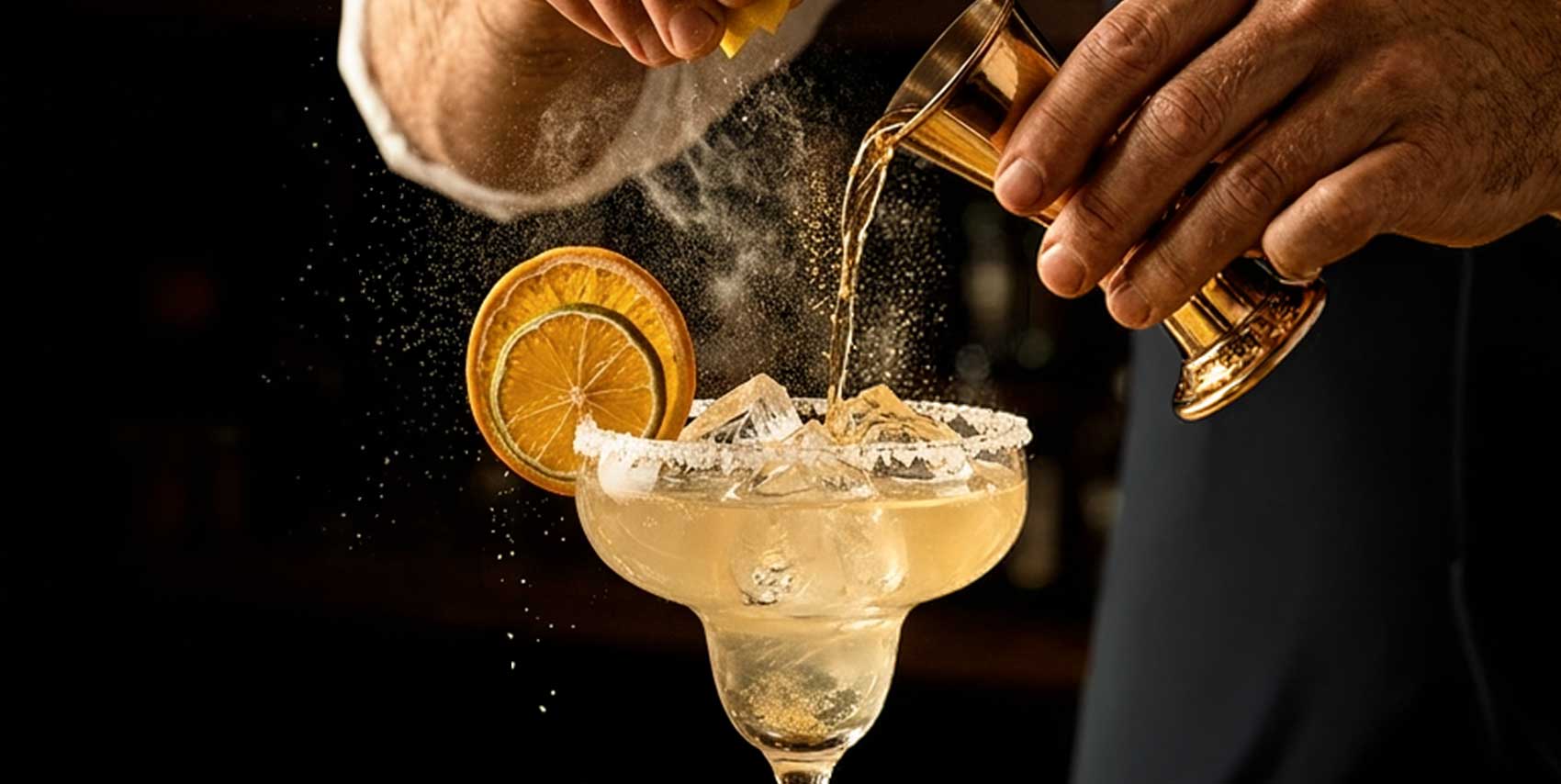 A bartender skillfully pours a margarita from a shaker into a glass, showcasing the drink's vibrant color.